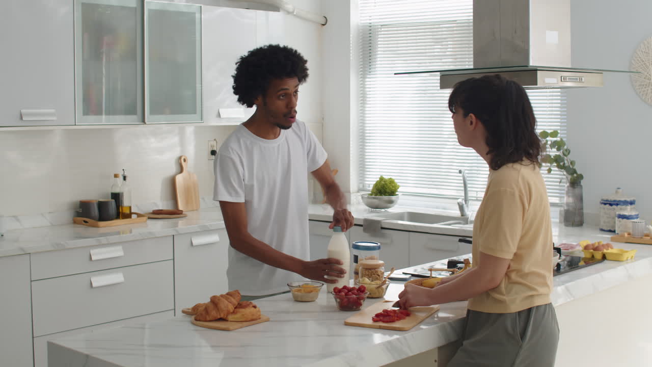 Una coppia felice che chatta mentre cucina insieme a casa