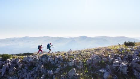 4k drone footage two backpackers walking by mountain ridge on sunny day with hiking poles