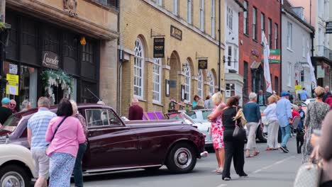 people admire vintage cars on a busy street