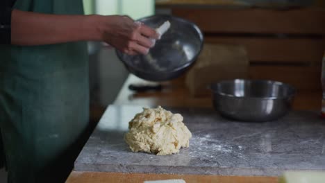 dough mix scraped out of steel bowl and placed in pile on granite tabletop, filmed as medium close up slow motion shot