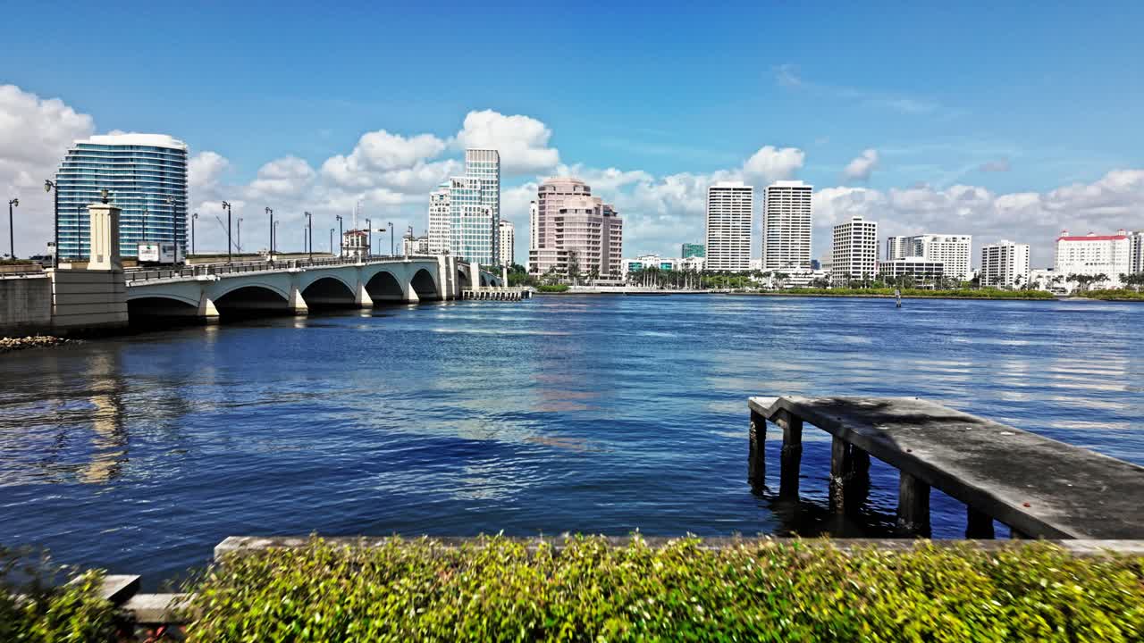 Aerial: cityscape from parking lot with Royal Park Bridge, One Flagler and Phillips Point building during the day in West Palm Beach, Florida, USA, establishing drone shot