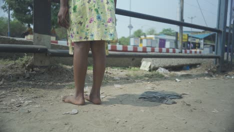 unrecognized poor asian dark skin girl walks bare feet and watches train passing by