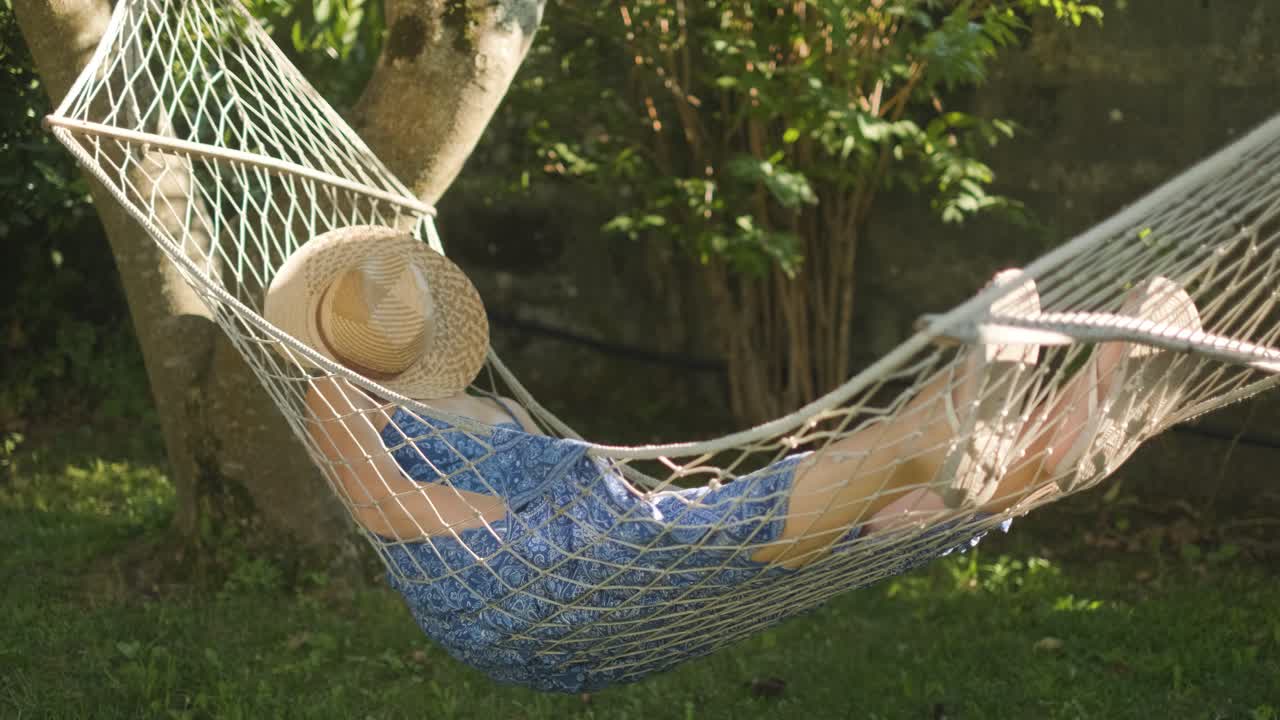 mujer tomando una siesta en una hamaca bajo la sombra del árbol