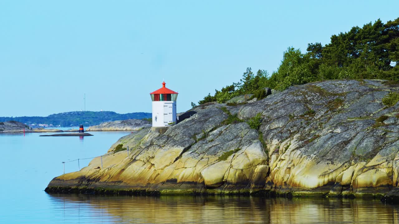 A small lighthouse on a rocky shore in Bohuslan, Sweden, by a peaceful sea