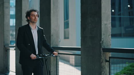 young man in a suit walking with an electric scooter in an urban setting