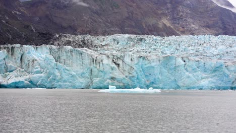 cracking ice wall and a glacial lake at a blue glacier in sunny alaska - pan view