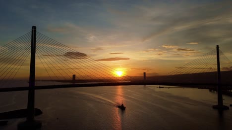 Cebu-Cordova-Link-Expressway,-Tug-boat-passing-by-against-beautiful-sunset