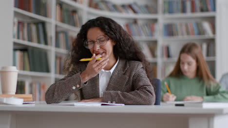 tired student struggles with exhaustion while studying in library