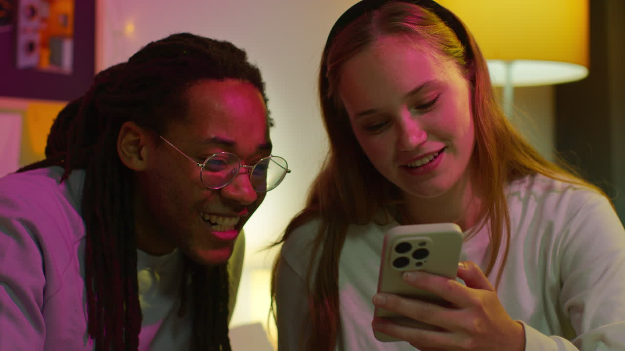 A couple laughing together while looking at a phone.