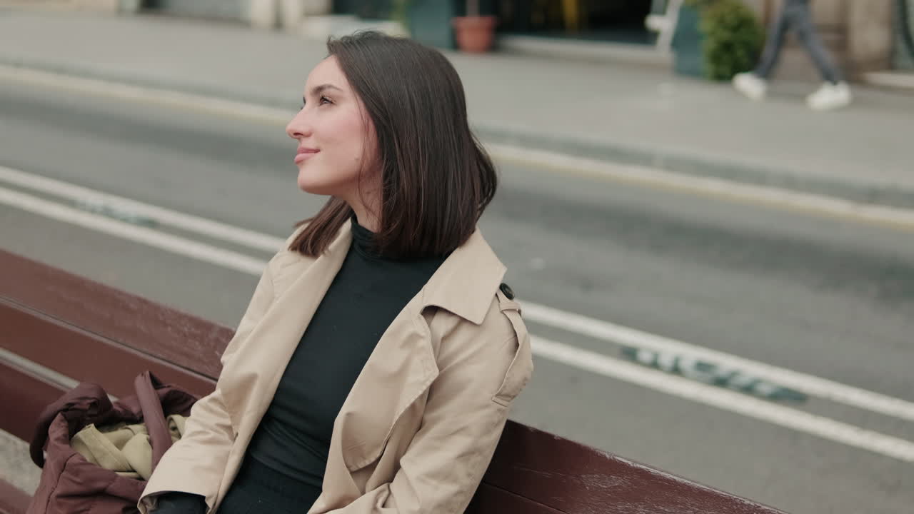 Giovane donna seduta su una panchina in città, che sorride e si rilassa