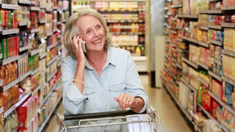 mujer mayor hablando por teléfono en el supermercado