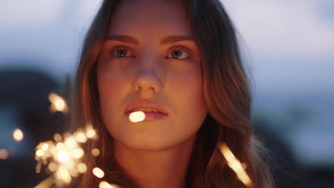 close-up-sparklers-portrait-of-attractive-caucasian-woman-celebrating-new-years-eve-enjoying-independence-day-celebration-on-beach-at-sunset