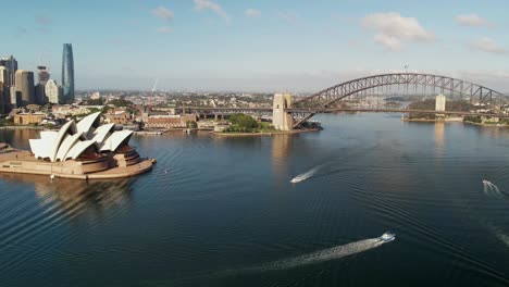 boats travelling around in sydney harbour with the bridge buildings and opera house