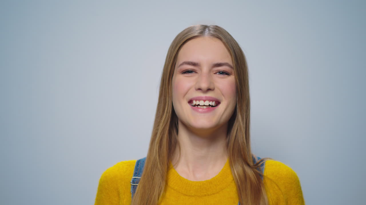 Portrait of happy woman smiling at camera on grey background in studio.