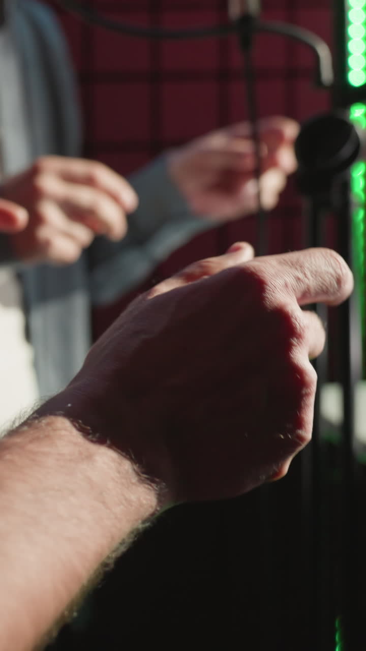 primer plano de dos hombres chasqueando los dedos rítmicamente en un estudio de grabación. un hombre lleva una camisa negra mientras el otro está fuera de foco en el fondo