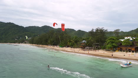 Aerial-following-kite-surfers-off-Sairee-Beach,-the-longest-beach-on-the-Koh-Pha-Ngan-island