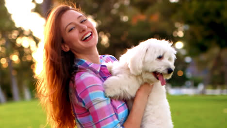 woman holding and hugging white dog at park