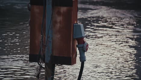caja eléctrica oxidada sumergida por el aumento de las aguas de inundación que se reflejan en el río
