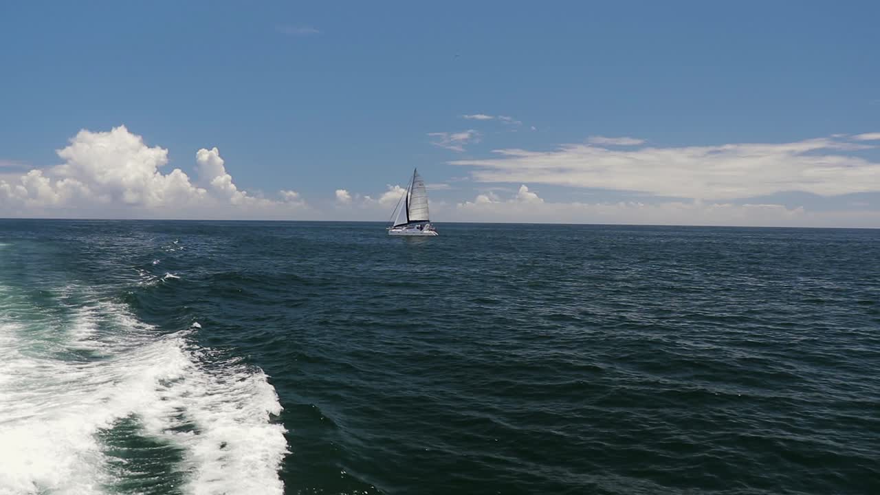 A shot of a Sailing yacht sailing in the distance. Filmed from a Catamaran with a Canon 200D on a Zhiyun-Tech Crane 2.