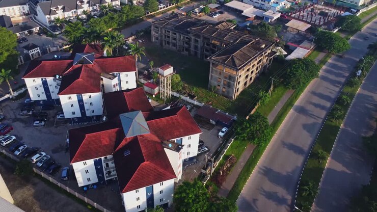 Drone che vola verso nuovi complessi di appartamenti nel nuovo quartiere Gudu ad Abuja, in Nigeria. Accanto si può vedere un edificio vidco di appartamenti non completato