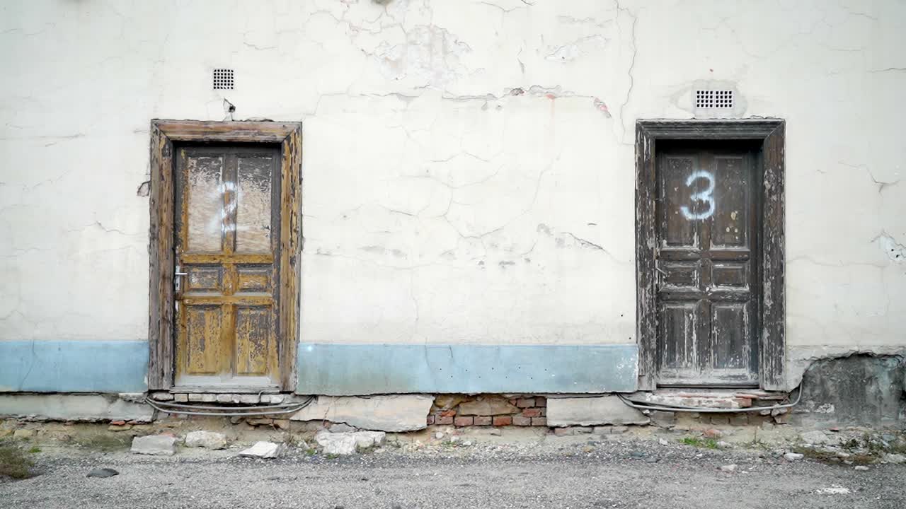 Two weathered wooden doors on a cracked wall