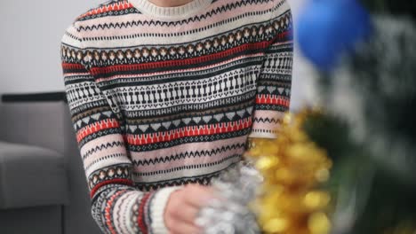 Closeup-view-of-woman's-hands-decorating-a-Christmas-tree-with-toys-in-modern-appartment.-Shot-in-4k