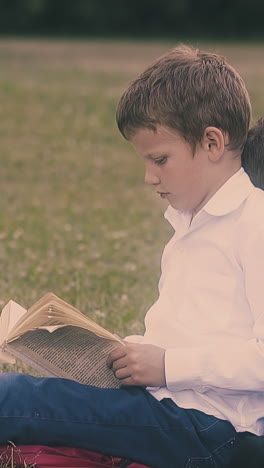 exhausted schoolboy in white shirt throws away book leaning on schoolmate during break sitting on lawn slow motion