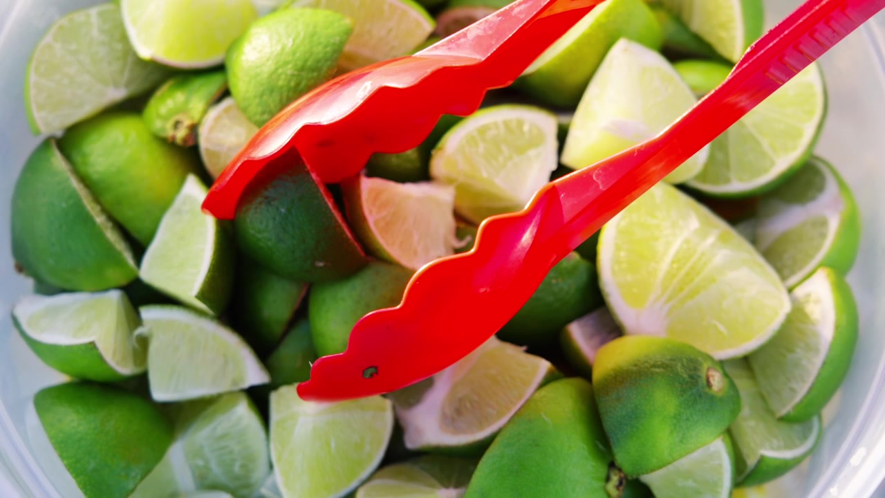Primo piano di spicchi di lime appena tagliati preparati presso una bancarella di taco da strada, che evidenzia vivaci ingredienti agrumati utilizzati per la preparazione di autentico cibo messicano e street food.