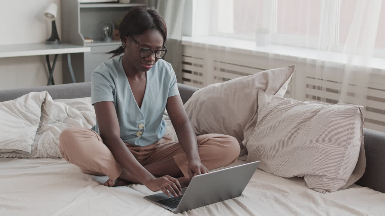Young African-American Woman Using Laptop in Bed