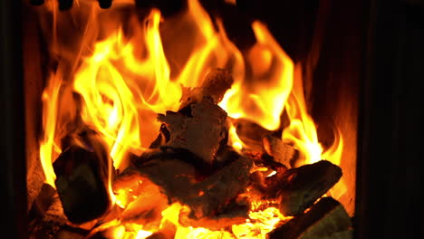 ember and firewood in flames in stove, static closeup view on yellow blaze