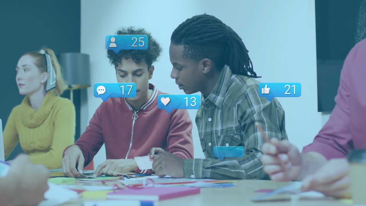 Collaborating at table, young adults discussing animation with social media icons