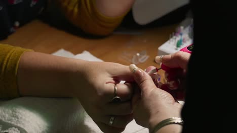 close-up of nail technician using an electric drill to shape polygel nails. gel excess removal and cuticle shaping