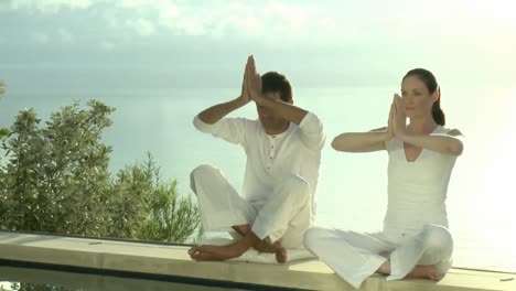 two persons doing yoga with sea in the background