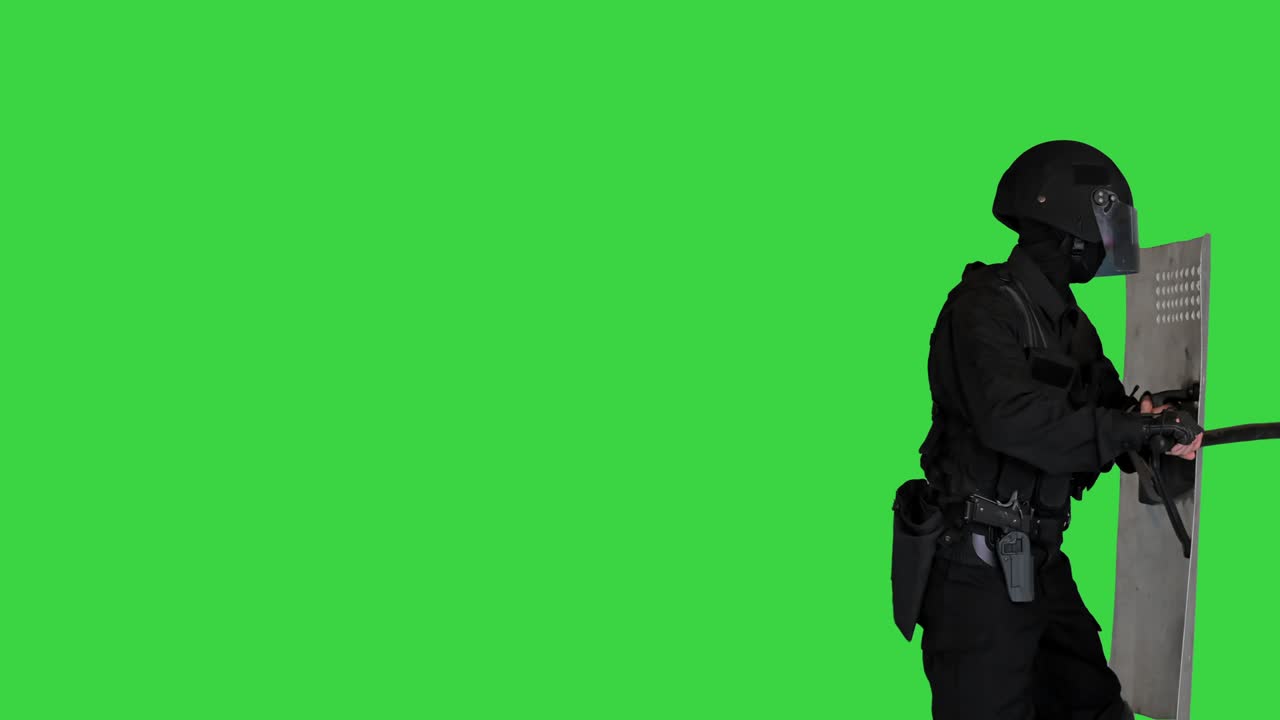Poliziotto con equipaggiamento antisommossa completo, con lo scudo alzato, che spinge e avanza su uno schermo verde, Chroma Key