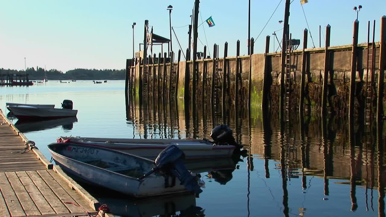 un pueblo de langostas en stonington maine está cerca de un muelle de madera que se refleja en el agua