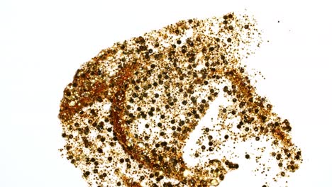 las pinceladas de pintura dorada aplicadas aisladas en un fondo rosado. la textura de la pintura dorada. el brillo, las estrellas, las chispas. la ilustración artística de textura dorada brillante. las manchas de cosméticos.