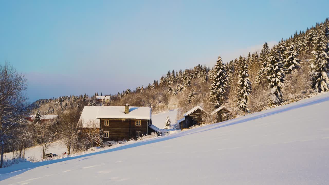 plano general de una casa de madera nevada ubicada en la ladera de la montaña durante el día soleado en invierno - árboles de abeto cubiertos de nieve y hielo en el fondo