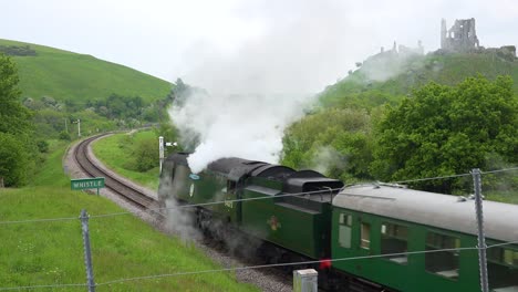 un viejo tren de vapor pasa por las ruinas del castillo de corfe dorset, inglaterra