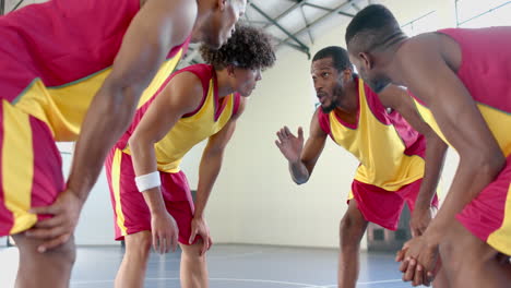 jugadores de baloncesto afroamericanos se agrupan en un gimnasio, discutiendo estrategia
