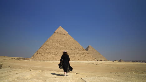 girl walking towards the pyramids of giza in cairo, egypt - wide shot