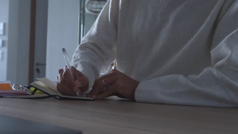 Man-sitting-at-a-desk-and-writing-down-his-goals-for-the-future-in-a-small-notebook,-concept-for-strategy,-ambition,-goal-setting,-and-New-Year's-Resolutions