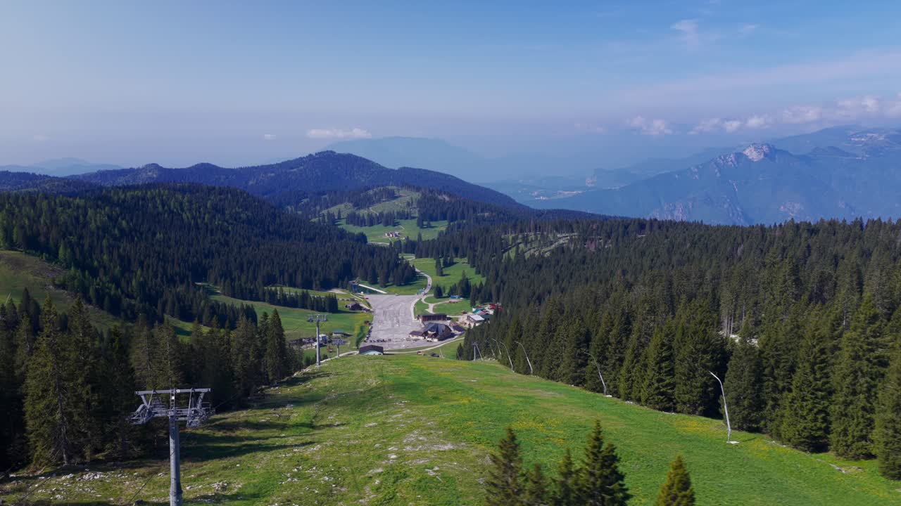 Expansive mountain landscape with dense forests, open meadows, and visible ski infrastructure
