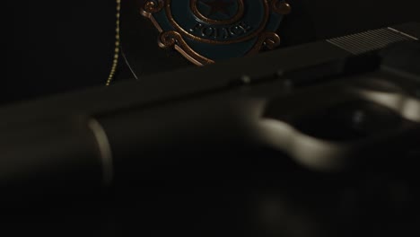 police badge and gun lying on a dark surface with flashing police lights