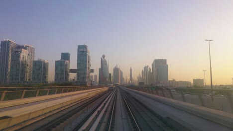 horizonte de paisaje urbano futurista de dubai al atardecer, vista desde el frente del tren de metro moviéndose en ferrocarril