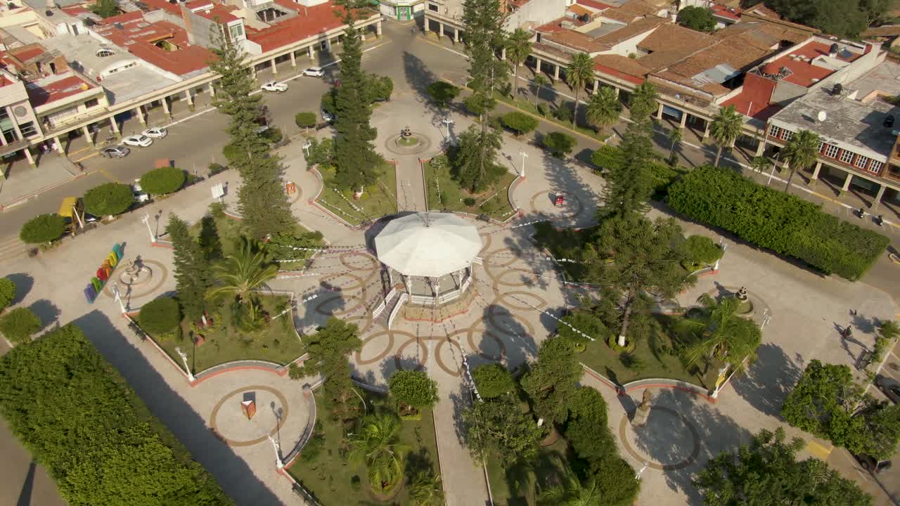 Aerial orbit view of central park with gazebo, trees and Mexican decorations in the small mexican town of Tuxpan, South of Jalisco