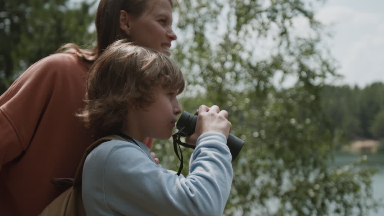 Boy and woman using binoculars in nature