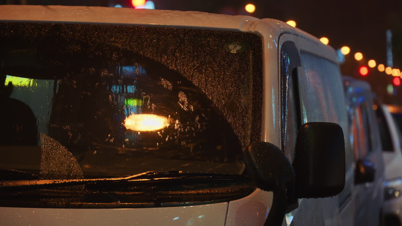 Raindrops hitting a white van on the street in the evening. Tokyo, Japan
