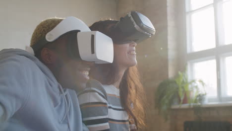 positive multiethnic couple using vr headsets for playing video game