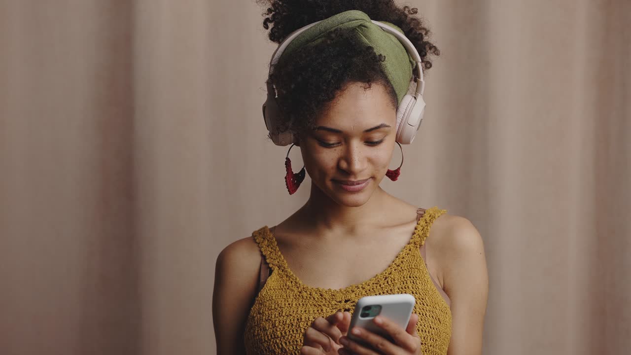 tecnologías modernas. retrato de una joven elegante dama afroamericana con auriculares eligiendo música en una aplicación en línea