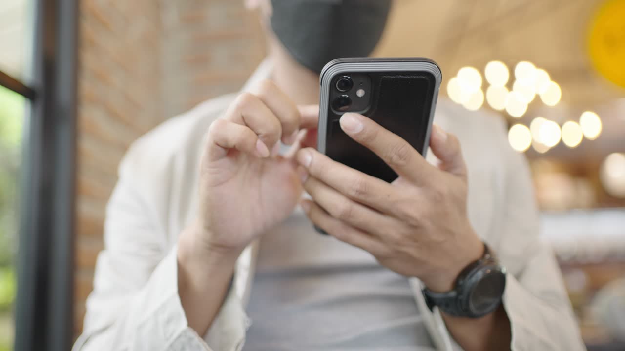 un joven empresario con una máscara quirúrgica está tomando una videoconferencia con los clientes a través de un teléfono inteligente conectado a internet.